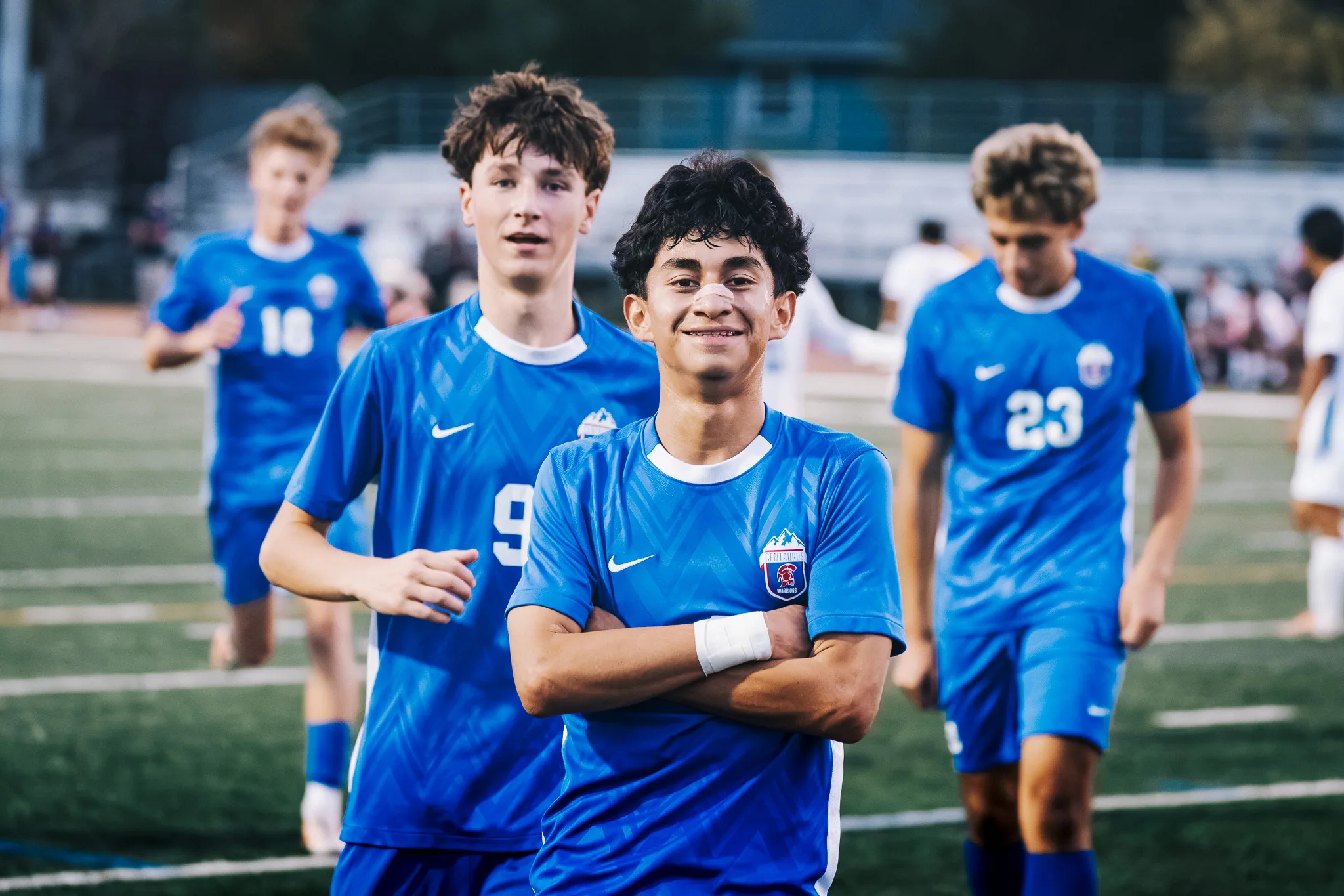 A grinning Centaurus player crosses his arms as his teammates walk up behind him