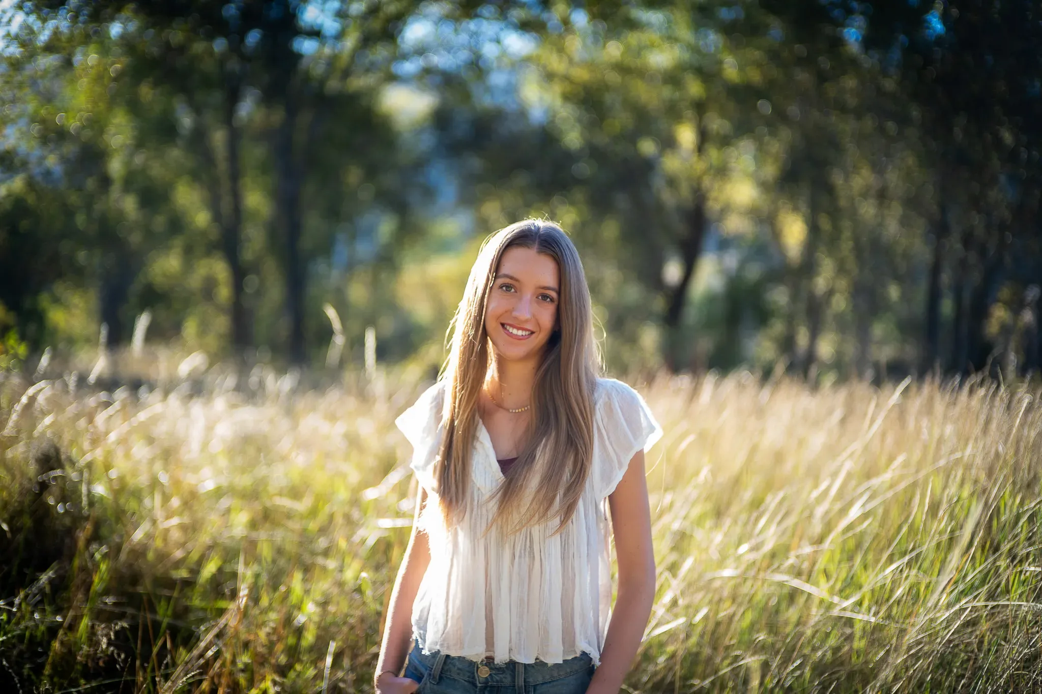 Young woman smiling in a sunlit grassy field